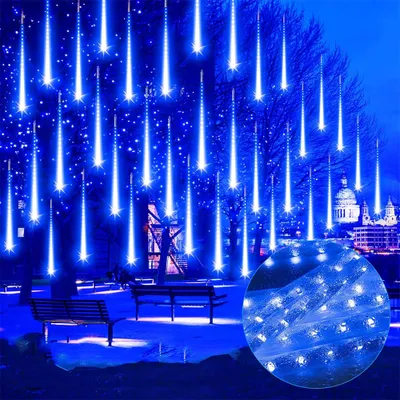 Blue meteor shower lights illuminate trees and a park at night, with buildings in the background.