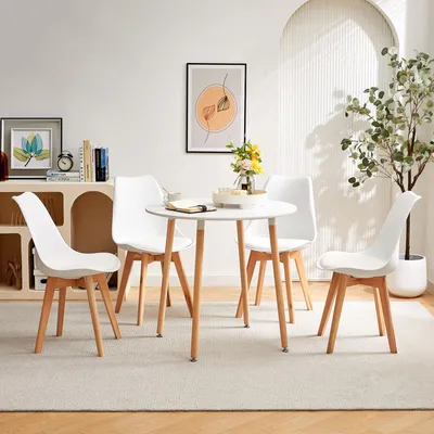 A white round dining table with four white chairs in a bright, minimalist room.