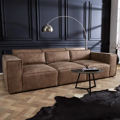 A modern living room scene featuring a large brown sofa, a floor lamp, and a coffee table.