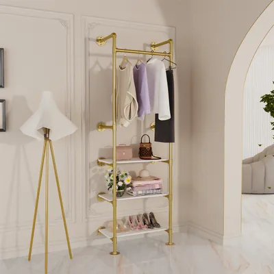 A gold industrial-style garment rack with shelves, decorated with clothing and accessories, is shown in a room with a floor lamp and an arched doorway.