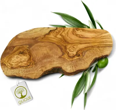 A rustic olive wood cutting board with a natural edge, adorned with olive leaves and a single olive. A brand tag is attached to the board.