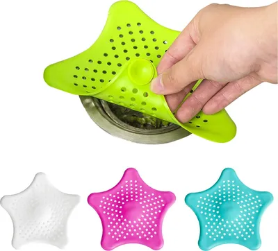 A hand is shown placing a green star-shaped drain cover over a sink drain. Below, three other drain covers in white, pink, and teal are displayed.
