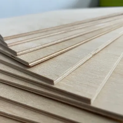 A stack of thin wooden boards, likely plywood, is shown from a close-up, diagonal angle.