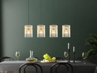 A dining table set with a decanter, grapes, and wine glasses, illuminated by four pendant lights.
