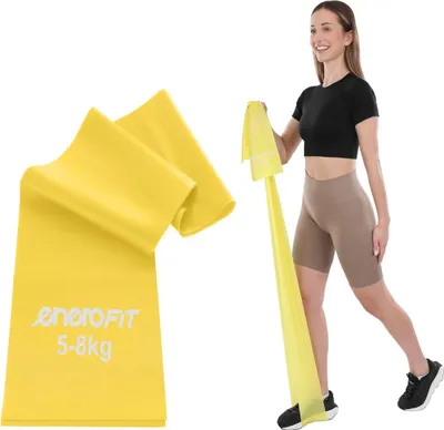 A woman is using a yellow resistance band for exercise, with a folded resistance band shown in the foreground.