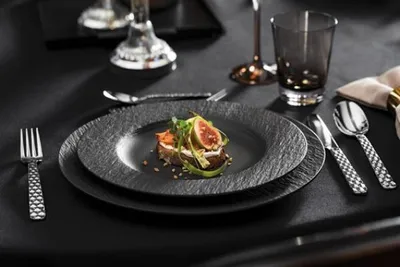 A table setting with a plate of food, cutlery, and glasses.