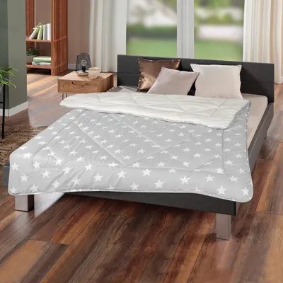 A bed with a star-patterned comforter and pillows in a bedroom setting.