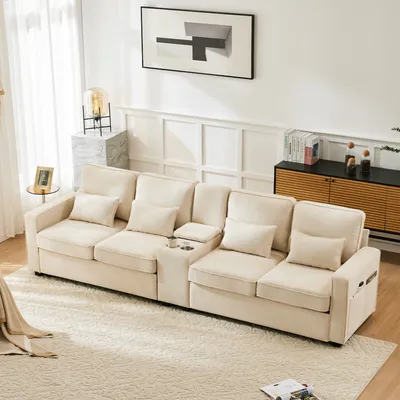 A cream-colored sectional sofa is arranged in a living room setting, with a rug underneath and a sideboard in the background.