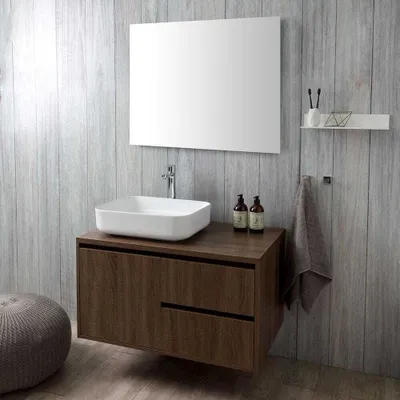 A modern bathroom vanity with a vessel sink and mirror against a wood-paneled wall.