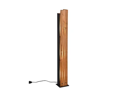 A tall, slender floor lamp made of wood with cutouts that allow light to shine through, standing on a black base with a black cord.