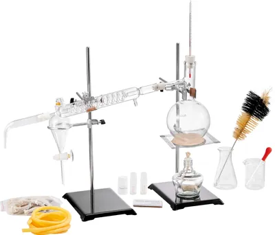 A laboratory distillation setup with various glass components and accessories, arranged on a white background.