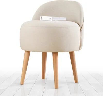 A beige upholstered stool with wooden legs sits on a white wooden floor.