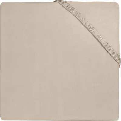 A close-up, top-down view of a beige fitted sheet with elastic gathering at one corner.