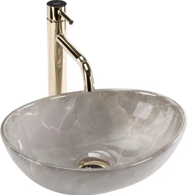 A close-up studio shot of a marble sink with a gold faucet.