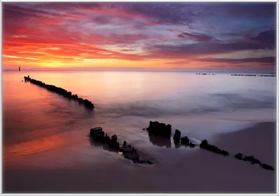 Produktbild von Wallario Wandbild Sandstrand im Sonnenuntergang - Roter Himmel, Größe: 70,30 x 100,30 cm, Poster mit weißem Kunststoffrahmen