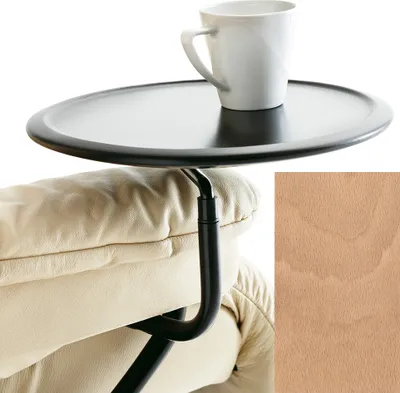 A close-up of a black tray table attached to a beige leather armchair, with a white mug on the tray. A swatch of wood texture is in the bottom right corner.