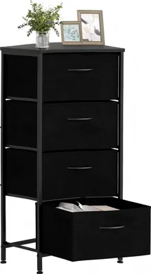 A black fabric dresser with four drawers is shown against a white background. The top drawer is slightly ajar, revealing some contents. Two framed pictures and a potted plant are placed on top of the dresser.
