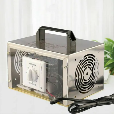 A silver ozone generator with a black handle is placed on a white surface with a light gray background. A green plant is visible on the right side.