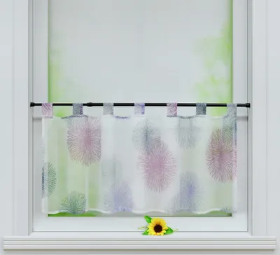 A short curtain with a colorful firework pattern hangs on a window rod. A single sunflower rests on the windowsill below.