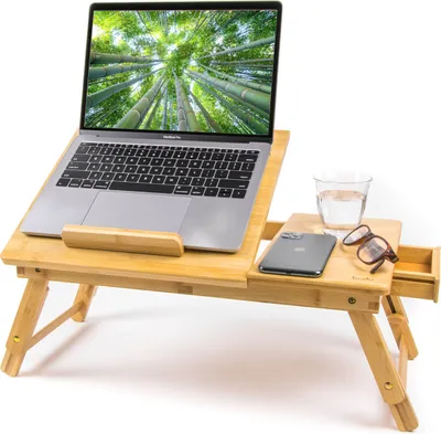 A bamboo laptop table with a laptop, phone, glasses, and a glass of water on it.