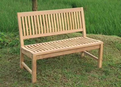 A wooden garden bench sits on a grassy area with a blurred green background.
