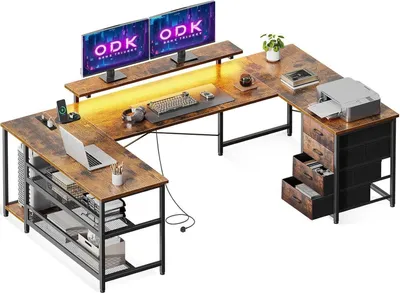 A large, L-shaped desk with multiple monitors, a laptop, a printer, and storage drawers.