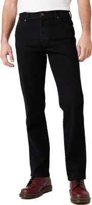 A person wearing black jeans and brown shoes, shown from the waist down.