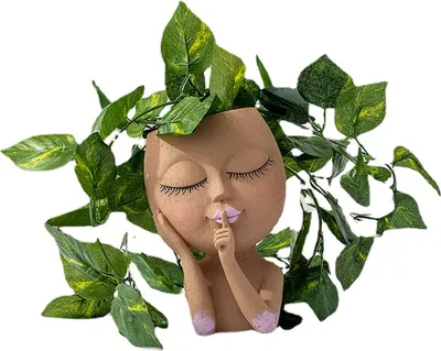 A planter shaped like a woman's head with plants growing out of it.