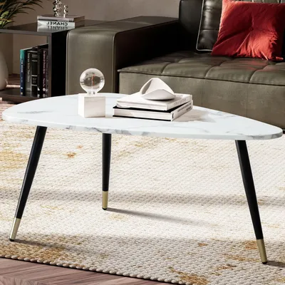 A triangular coffee table with a marble-like top and black legs with gold accents, placed on a rug in a living room setting.