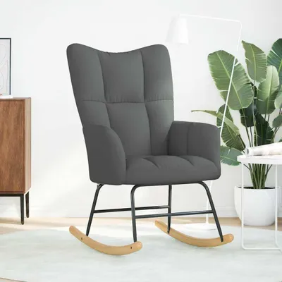 A dark gray rocking chair in a room with a white wall and a wooden cabinet.