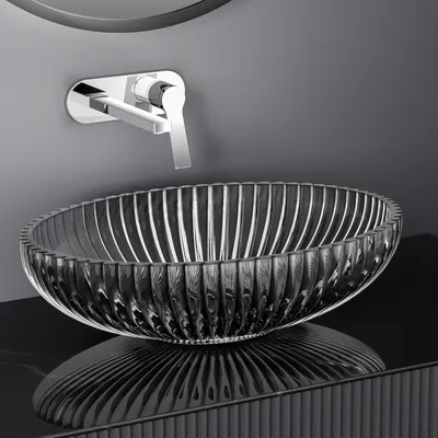 A modern bathroom sink setup with a glass basin and a wall-mounted faucet.