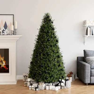 A decorated Christmas tree with presents underneath, next to a fireplace and a sofa.