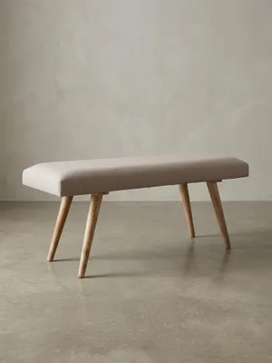 Beige Stoffbank im Retro-Stil frontal freigestellt. Die klare rechteckige Form, das 12 cm dicke Polster und die konischen Massivholzbeine unterstreichen das zeitlose Design._#sku_BARWL5.329#