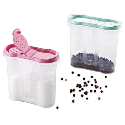 Two spice containers, one pink and one green, are shown against a white background. The pink container is filled with white granules, possibly salt, and has its lid open, revealing a perforated dispenser. The green container is filled with peppercorns and 