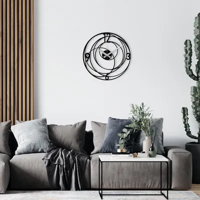 A modern living room with a grey sofa, decorative pillows, a coffee table, and a large abstract wall clock.