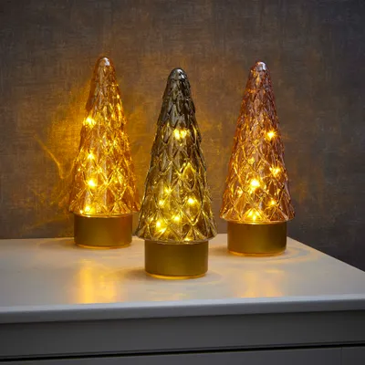 Three decorative glass Christmas trees with LED lights sit on a white surface against a textured gray background.
