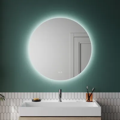 A round LED bathroom mirror is mounted on a teal wall above a white sink.