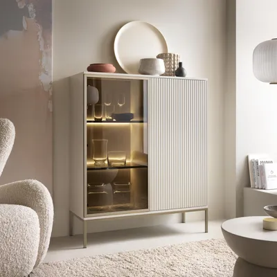A modern living room setting with a display cabinet and armchair.