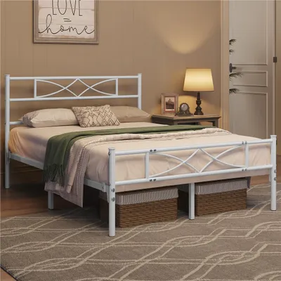 A white metal bed frame with a mattress and bedding, set in a bedroom with a bedside table and lamp.
