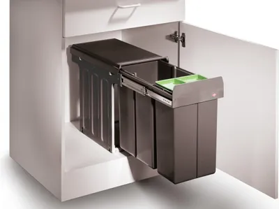 A pull-out kitchen bin system with multiple compartments inside a cabinet.