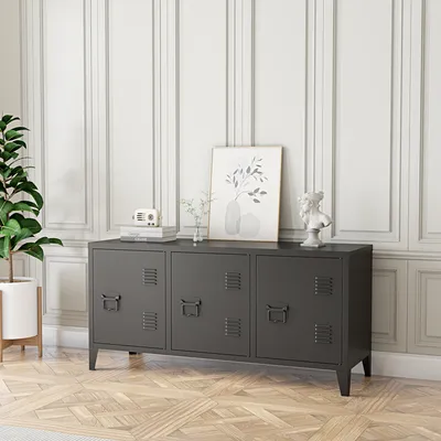 A dark gray metal cabinet with three doors stands against a white paneled wall, with a plant to the left and decorative items on top.