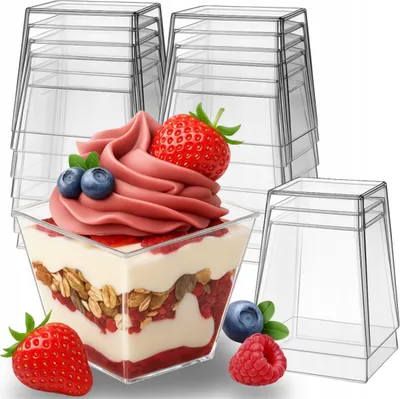 A stack of clear plastic dessert cups, with one cup filled with a layered dessert and topped with soft-serve ice cream, berries, and granola.