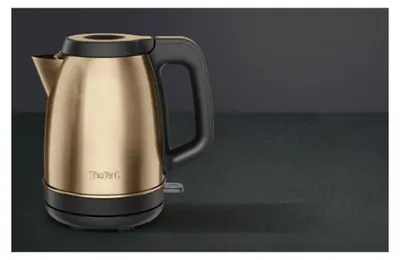 A copper and black electric kettle is displayed against a dark gray background.