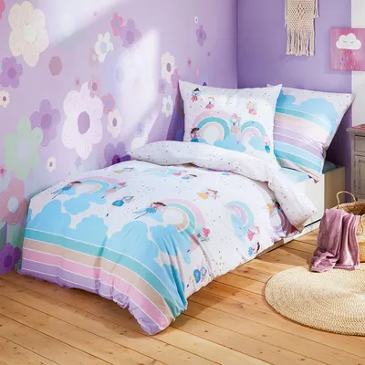 A child's bedroom with a bed dressed in colorful bedding featuring rainbows and fairies.