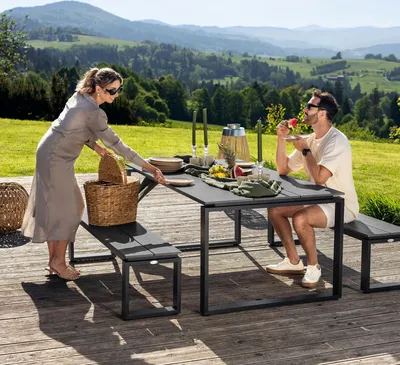 A couple enjoying a meal outdoors on a patio with a scenic mountain view.