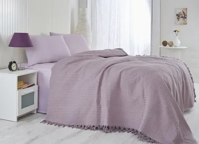 A neatly made bed with purple bedding and a blanket.
