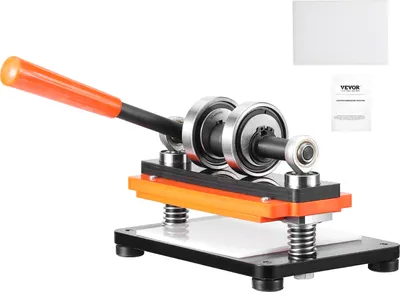 A leather die-cutting machine with an orange handle and silver rollers is shown against a white background. There are also two small white rectangles and a booklet with text on them in the upper right corner.