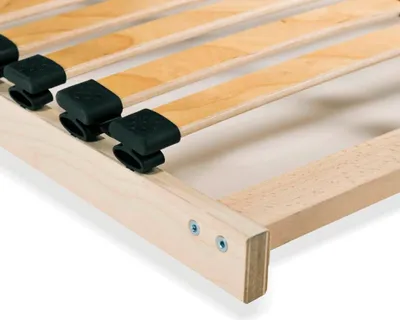 A close-up view of a wooden bed frame with black plastic slat holders.