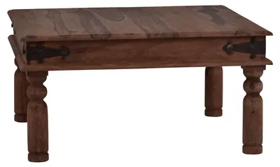 A wooden coffee table with ornate legs and metal hinges on the sides.