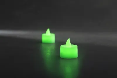 Two green LED tea lights on a dark surface.